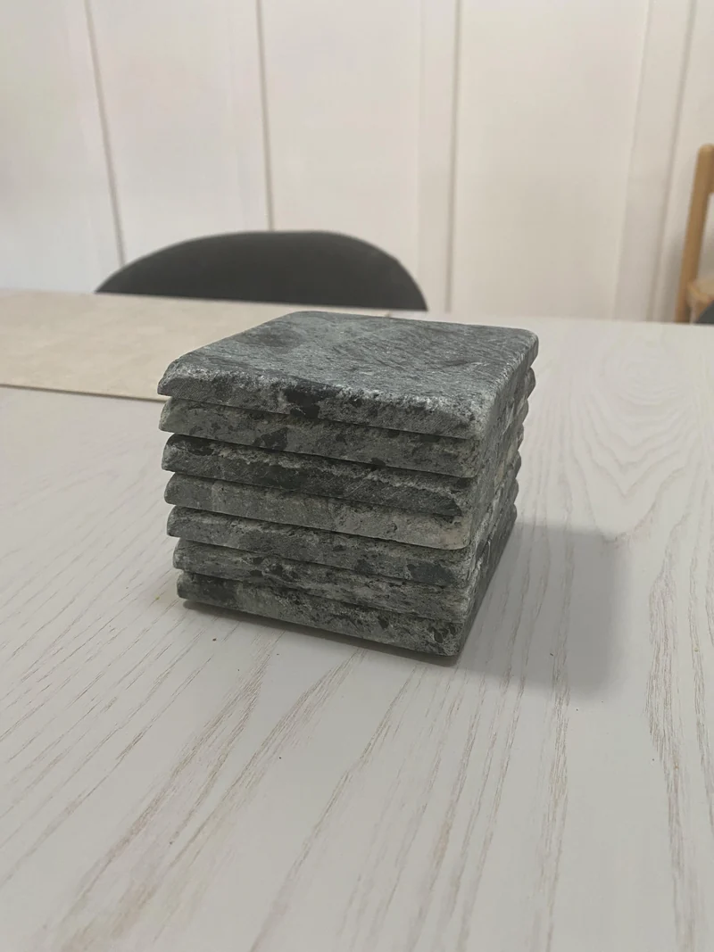 Stack of grey stone coasters with textured edges
