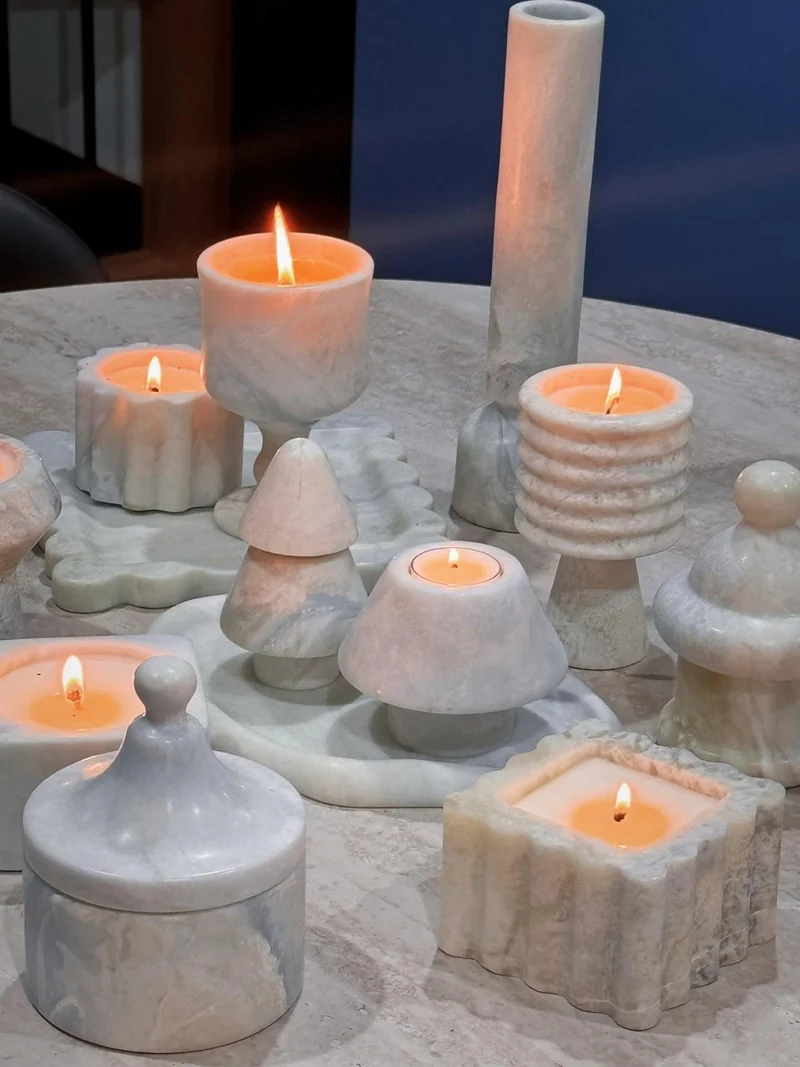 Pale stone candle vessels and lidded forms of different profiles arranged on a table