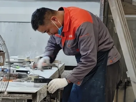 DeHong Stone worker using a hand-held tool to finish the edge of a stone piece