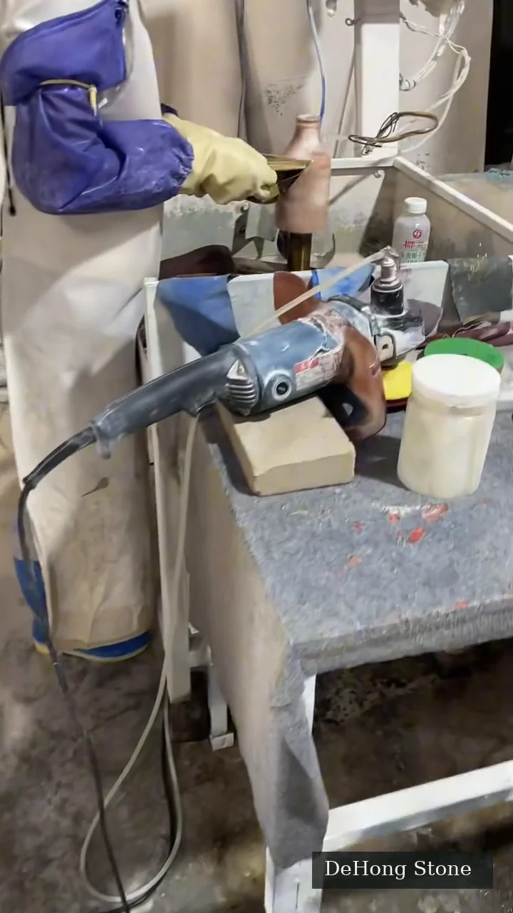 Hands working on a small stone piece at a workshop bench, still from the supplied silent processing film
