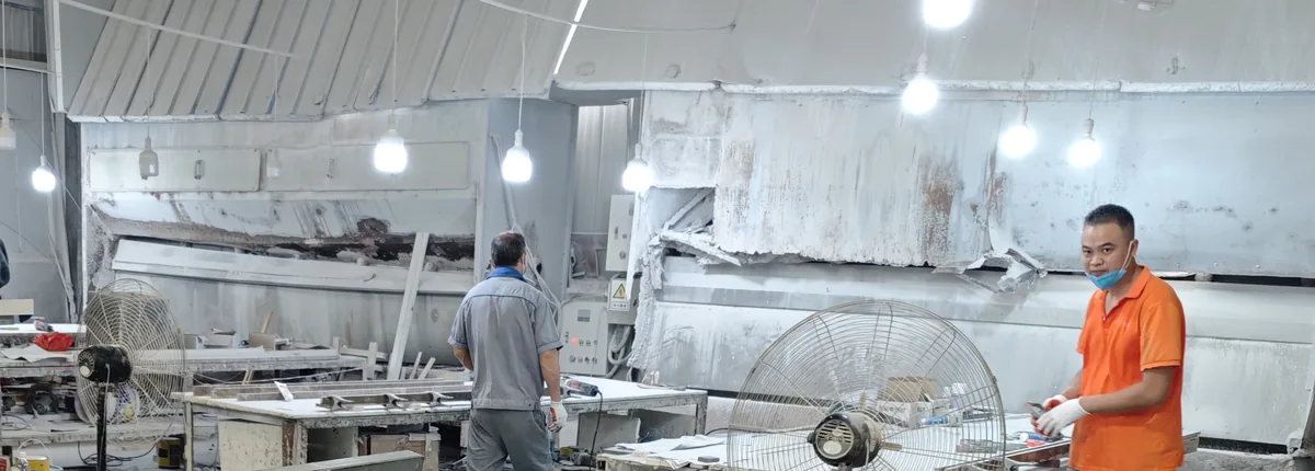 Workers at stone-processing benches beneath extraction hoods in the DeHong Stone workshop